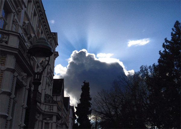 Die Sonne lugt hinter dunklen Wolken hervor.